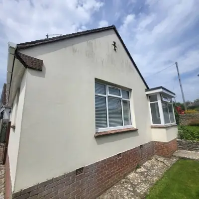 Bungalow gable end with dark algae streaks running down the render